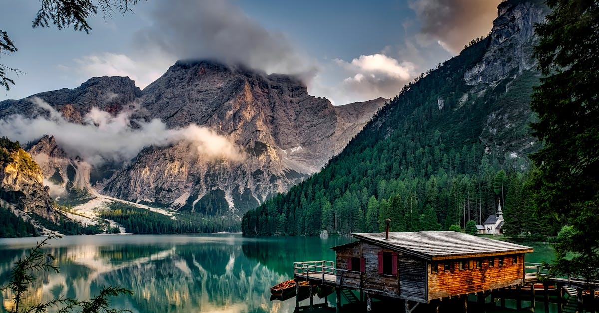 Peaceful mountain lake scene featuring a rustic boathouse and stunning reflections.